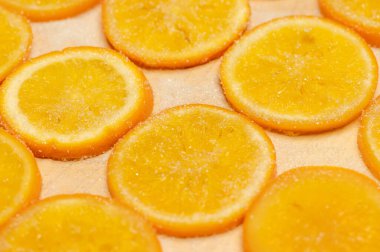 Kurutulmuş portakal dilimleri üzerine şeker serpiştirilmiş.