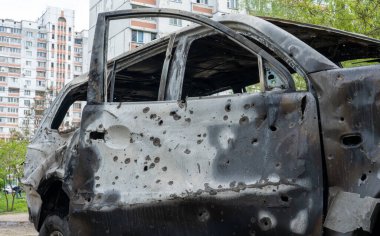 Rusya 'nın Ukrayna' ya karşı savaşı, Ukrayna halkının soykırımı, Rusya 'nın Kyiv' e düzenlediği en büyük füze saldırısı sonrasında kırık camlı bir evin önünde şarapnel delikleri olan yanmış bir araba.