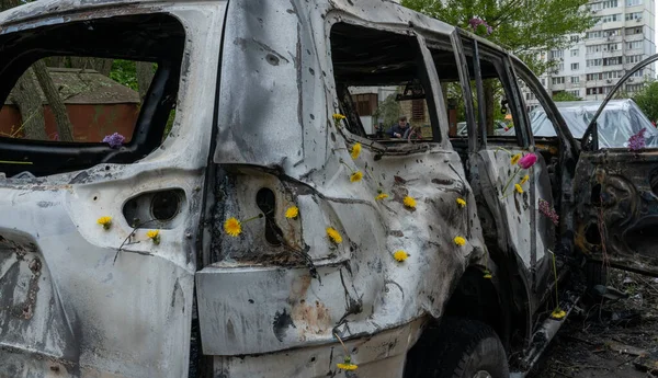 stock image Dandelions inserted into bullet and shrapnel holes in the hull of the civilian transport damaged by the missile attack on Kiev, Ukrainian Spring, the concept of war and peace, Russia's war