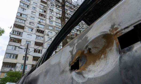 stock image A burnt car with shrapnel holes in front of a house with broken windows after Russia's biggest missile attack on Kyiv, the concept of Russia's war against Ukraine, the genocide of the Ukrainian people