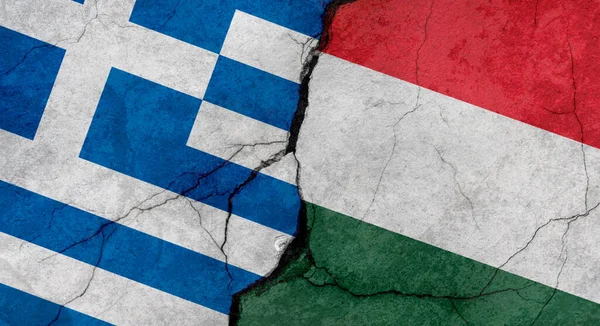 Greece and Hungary flags, concrete wall texture with cracks, grunge background, military conflict concept