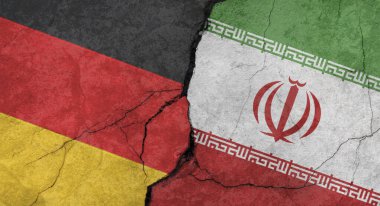 Almanya ve İran bayrakları, çatlaklı beton duvar dokusu, turuncu arka plan, askeri çatışma konsepti