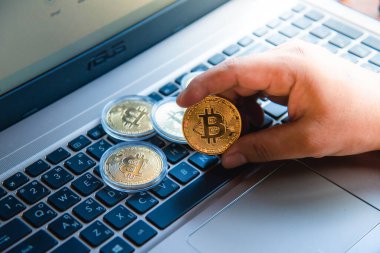 İşadamının elinde dizüstü bilgisayarda altın bir Bitcoin var. Bitcoin ile para kazanmak, dijital para birimi para yatırım konsepti, engelleme zinciri transferi.