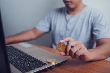 İşadamı dizüstü bilgisayarında altın bir Bitcoin tutuyor. Bitcoin ile para kazanmak, dijital para birimi para yatırım konsepti, engelleme zinciri transferi.