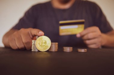 Elinde altın Bitcoin ve kredi kartı olan bir adam. Bitcoin ile para kazanmak, dijital para birimi para yatırım konsepti, engelleme zinciri transferi.