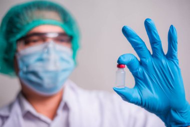 Doctor holding flu vaccine on beige background, medicine and drug concept. Vaccination against Coronavirus covid-19 pandemic.