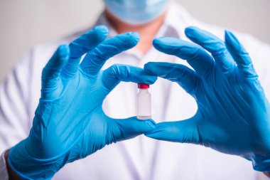 Doctor holding flu vaccine on beige background, medicine and drug concept. Vaccination against Coronavirus covid-19 pandemic.
