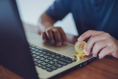 Adam bilgisayar, kripto para birimi modern finansal konsept kullanırken küçük alışveriş arabasına bitcoin koyuyor..