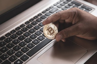 İşadamının elinde dizüstü bilgisayarda altın bir Bitcoin var. Bitcoin ile para kazanmak, dijital para birimi para yatırım konsepti, engelleme zinciri transferi.