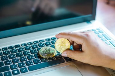 İşadamının elinde dizüstü bilgisayarda altın bir Bitcoin var. Bitcoin ile para kazanmak, dijital para birimi para yatırım konsepti, engelleme zinciri transferi.
