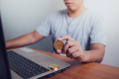 İşadamı dizüstü bilgisayarında altın bir Bitcoin tutuyor. Bitcoin ile para kazanmak, dijital para birimi para yatırım konsepti, engelleme zinciri transferi.