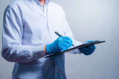 doctor working with clipboard of medication history records in clinic at his working place, closeup. Perfect medical service in hospital.