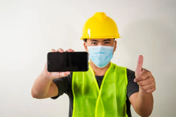 Engineer in medical mask holding smartphone.
