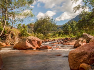 Orta Kolombiya 'nın doğu kesimindeki Andean dağlarında, Arcabuco kasabası yakınlarında, El Valle nehrinin kayaları ve kırsal asma köprüsünün uzun pozlu fotoğrafları..