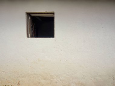 Kolombiya 'nın orta kesimindeki doğu Andean dağlarında, Arcabuco kasabası yakınlarında yıpranmış bir çiftlik evinin beyaz duvarında küçük bir kırsal açık kare pencere..