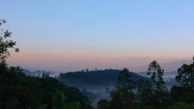 Güneşin doğuşunun diğer tarafındaki tepelerde, biraz sis ve Orta Kolombiya 'nın doğu Andean dağlarında açık mavi bir gökyüzü..