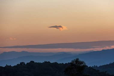 A very little cloud floats at the horizon, in a beautiful dusk over the eastern Andean mountains of central Colombia. clipart