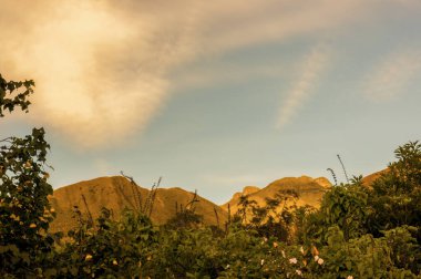 Günbatımı ışıklarıyla aydınlatılan Iguaque dağı, Orta Kolombiya 'nın doğusundaki Villa de Leyva kasabası yakınlarındaki And Dağları' ndaki bir çiftlikten alınan çoklu maruz kalma bileşimi..
