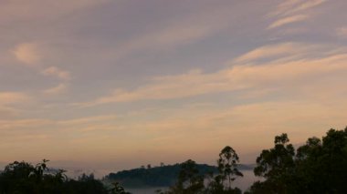 Rengarenk, yavaş bulutların altında, Orta Kolombiya 'nın doğu Andean dağlarında, Iguaque doğal rezervi yakınlarında, şafak vakti tarlalar üzerinde hareket eden zaman aşımına uğrayan sis..