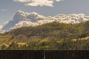 Dağın tepesinde yoğun parlak bir kümülüs bulutu, bir çiftliğin metalik kapısının arkasında, Orta Kolombiya 'nın doğu And Dağları' ndaki Cucaita kasabasında..
