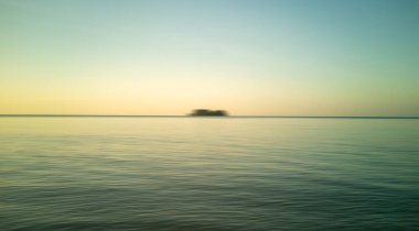 Gün doğumu sahili ve siyah siluet hareket bulanıklığı. Doğa arkaplan denizi, altın akşam gökyüzü ve bulanık ada.