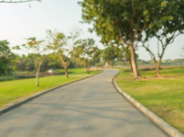 Bulanık bir park, gölet, ağaçlar ve bulutsuz bir gökyüzü.