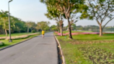 Bulanık bir park, gölet, ağaçlar ve bulutsuz bir gökyüzü.