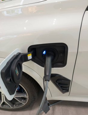 Beyaz elektrikli araba, şarj oluyor. Çevre için modern EV teknolojisi