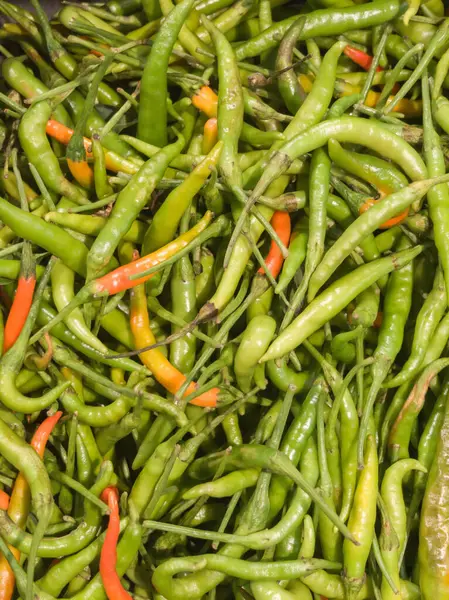 Süpermarkette kırmızı biber yığını. Baharatlı yiyecekleri parlak yeşille kapat..