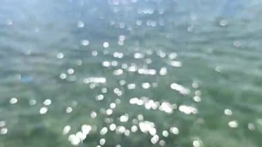 4K gerçek zamanlı video kaydı. Bulanık deniz suyu ve tropikal öğleden sonra güneşinden köpüklü bokeh.