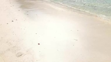 4K gerçek zamanlı video kaydı. Açık deniz dalgaları sıcak ve güneşli bir öğleden sonra sahilde nazikçe dalgalanır..