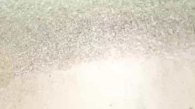 4K gerçek zamanlı video kaydı. Açık deniz dalgaları sıcak ve güneşli bir öğleden sonra sahilde nazikçe dalgalanır..