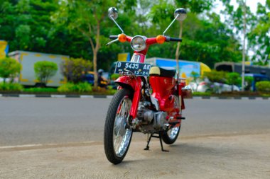 Otomotiv fotoğrafçılığı. Endonezya 'nın Bandung şehrinin üst geçidinin önünde poz veren klasik Honda Super Cub C90 süper Deluxe portresi.