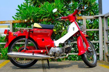 Otomotiv fotoğrafçılığı. Klasik Honda Super Cub C90 Super Deluxe kırmızı ve beyaz Endonezya Bandung 'da bir alışveriş merkezinin çatısına park edilmiş.