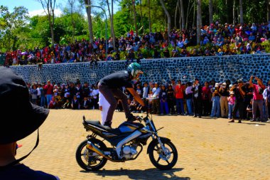 Bandung, Batı Cava, Endonezya - 17 Ağustos 2023: Indonezya 'daki 78. Bağımsızlık Günü Festivali' nde motosiklet dublörlerinin gösterilerini izleyen vatandaşların coşkusu. Sahanın ortasında motosiklet kullanan bir dublör..