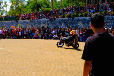 Bandung, Batı Cava, Endonezya - 17 Ağustos 2023: Indonezya 'daki 78. Bağımsızlık Günü Festivali' nde motosiklet dublörlerinin gösterilerini izleyen vatandaşların coşkusu. Sahanın ortasında motosiklet kullanan bir dublör..