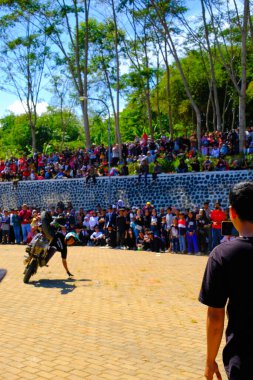 Bandung, Batı Cava, Endonezya - 17 Ağustos 2023: Indonezya 'daki 78. Bağımsızlık Günü Festivali' nde motosiklet dublörlerinin gösterilerini izleyen vatandaşların coşkusu. Sahanın ortasında motosiklet kullanan bir dublör..