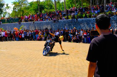 Bandung, Batı Java, Endonezya - 17 Ağustos 2023: Bir dublör Endonezya 'nın 78. bağımsızlık günü festivalinde motosiklet kullanarak serbest gösteri yapıyor, canlı bir kalabalıkla performans sergiliyor.