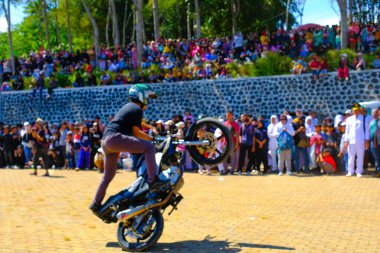 Bandung, Batı Java, Endonezya - 17 Ağustos 2023: Bir dublör Endonezya 'nın 78. bağımsızlık günü festivalinde motosiklet kullanarak serbest gösteri yapıyor, canlı bir kalabalıkla performans sergiliyor.