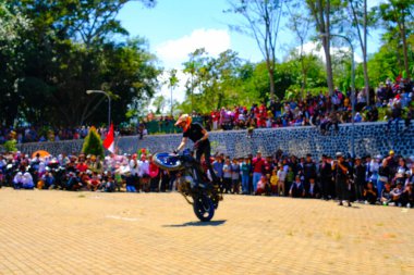 Bandung, Batı Java, Endonezya - 17 Ağustos 2023: Bir dublör Endonezya 'nın 78. bağımsızlık günü festivalinde motosiklet kullanarak serbest gösteri yapıyor, canlı bir kalabalıkla performans sergiliyor.