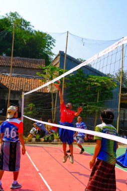 Bandung, Batı Cava, Endonezya - 17 Ağustos 2023: Bir grup orta yaşlı adam Endonezya 'nın 78. bağımsızlık günü, eğlenceli ve ferahlatıcı bir yarışma için voleybol müsabakası düzenliyorlar.