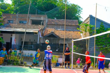 Bandung, Batı Cava, Endonezya - 17 Ağustos 2023: Bir grup orta yaşlı adam Endonezya 'nın 78. bağımsızlık günü, eğlenceli ve ferahlatıcı bir yarışma için voleybol müsabakası düzenliyorlar.