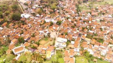 Manzara görüntüsü. Havadan manzaralar. Bandung 'un kenar mahalleleri, yoğun yerleşim alanları, köy yolları, tepeler ve pirinç tarlaları. 4K çözünürlüğündeki bir insansız hava aracından havadan ateş edildi..