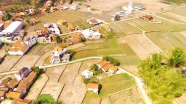 Endüstriyel Video. Yüksek hızda çekim. Kırsaldaki pirinç tarlalarının aşırı hızlı görüntüsü. Yerleşim alanları ve ağaçları olan güzel pirinç tarlaları. Uçan bir drondan havadan ateş edilmiş. Bandung - Endonezya, Asya