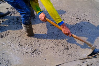 Sanayi fotoğrafçılığı. İnşaat işleri. İşçiler çimento dökmek için kum ve taşlarla çimento çapalıyor ve karıştırıyorlar. Bandung - Endonezya, Asya
