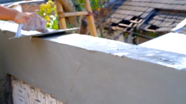 インダストリアル ビデオ 建設工事について フッテージ建設の従業員は コンクリート壁の質感にモルタルを適用することに取り組んでいます コンクリートの壁のテクスチャーに取り組んでいる人間の手の近く インドネシア — ストック動画