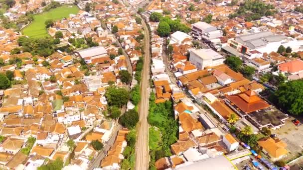 ドローン フッテージ インドネシア西ジャワ州の鉄道線の航空観測 長い列車が人口密度の高い地域を通過する ビデオは4K 30Fps解像度で撮影されています — ストック動画