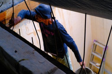 Bandung, Batı Java, Endonezya - 27 Aralık 2023: Sanayi Fotoğrafçılığı. Mavi gömlekli adam köşe yazısı yazıyor. Oyuncuları ve sütunu bir spatula kullanarak düzleştir.