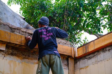 Bandung, Batı Java, Endonezya - 27 Aralık 2023: Sanayi Fotoğrafçılığı. Mavi gömlekli adam köşe yazısı yazıyor. Oyuncuları ve sütunu bir spatula kullanarak düzleştir.