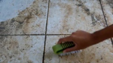Ev yapımı videografi. Elle çekim. Kabuklu zemini fırçalayan ev işleri. Beton kaplı zemin temizleniyor. 4K çözünürlükte 30 Fps.